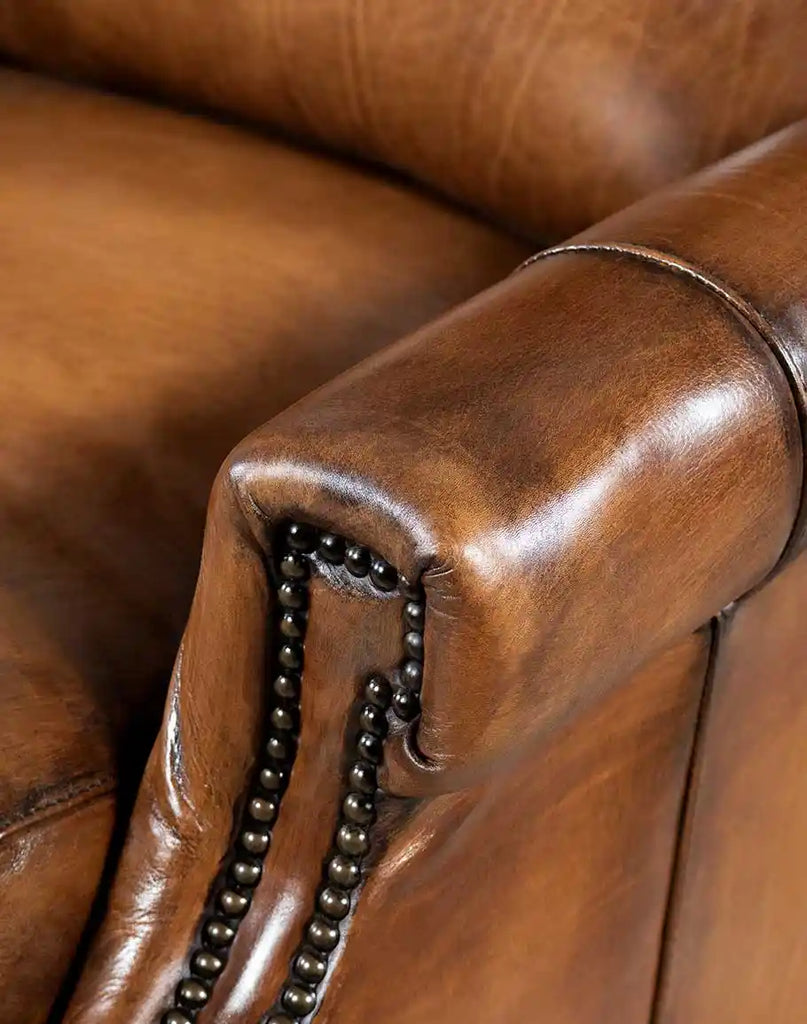 A close-up of the armrests on the Stanford Brown Leather Recliner, highlighting the smooth leather and brass nail accents.