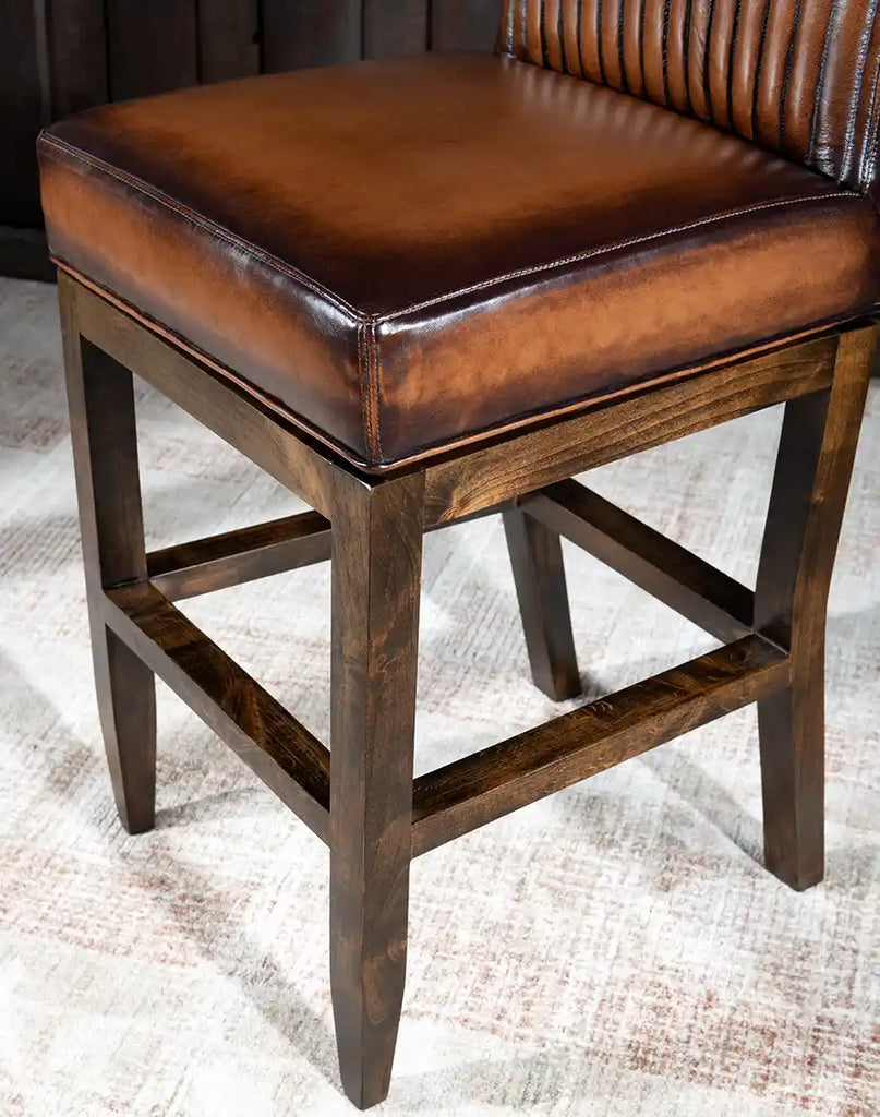 A close-up of the strong wooden legs on the Stanley Leather Barstool, complete with a built-in footrest for enhanced comfort and support.