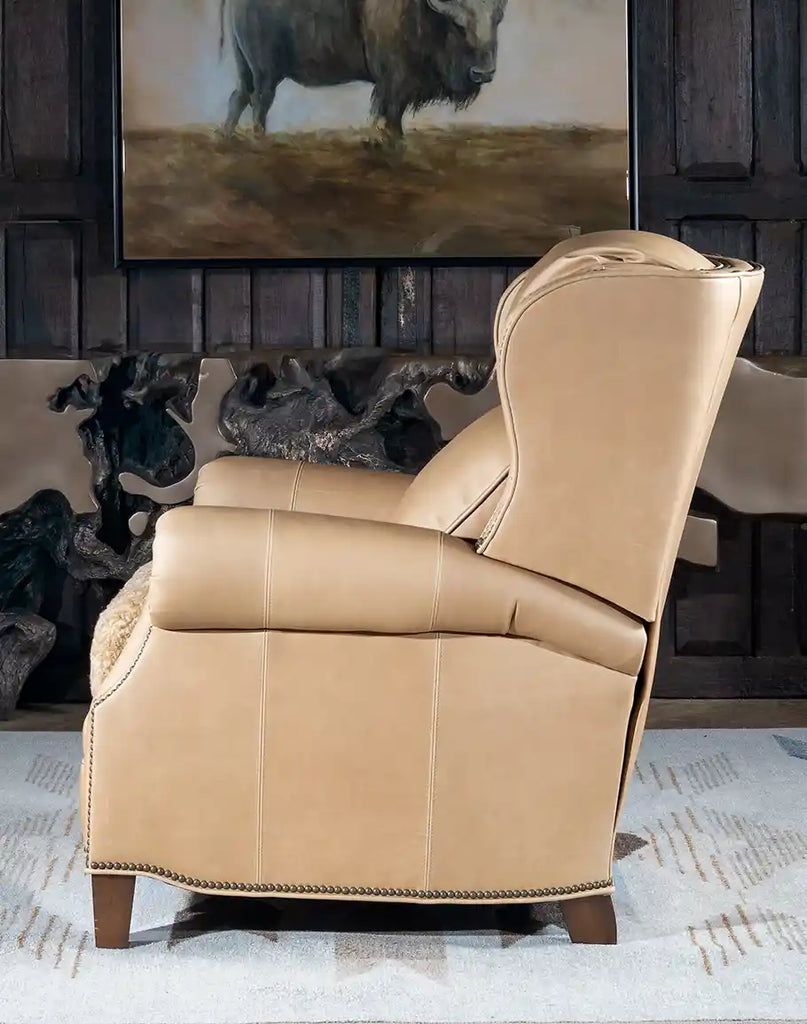 Angled side view of the Stanley Sandstone Recliner, highlighting the bustle back design and elegant brass nail tacks along the armrests.