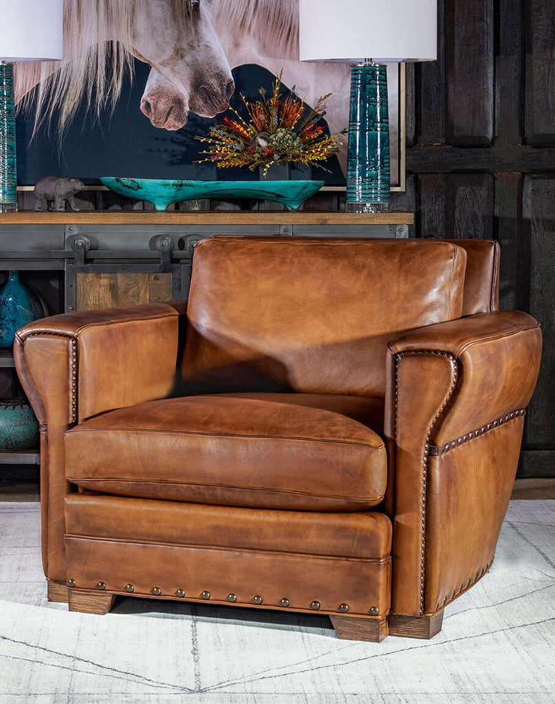 Front view of the Stockman Leather Chair showcasing its rustic leather and tapered armrests.