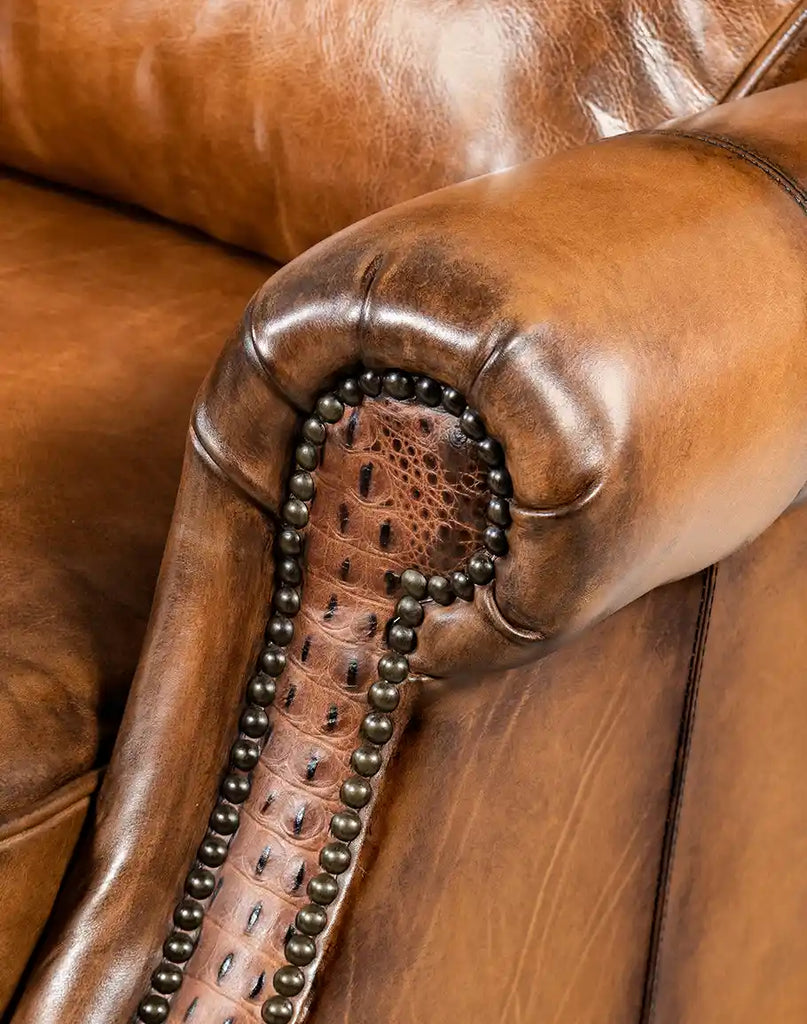 Close-up view of the armrest on the Tan Bronco Leather Recliner with embossed leather and brass nail tack detailing.