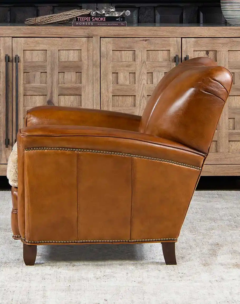 Side view of Tan Saddle Club Chair emphasizing the channeled backrest and the cream shearling hide seat cushion.