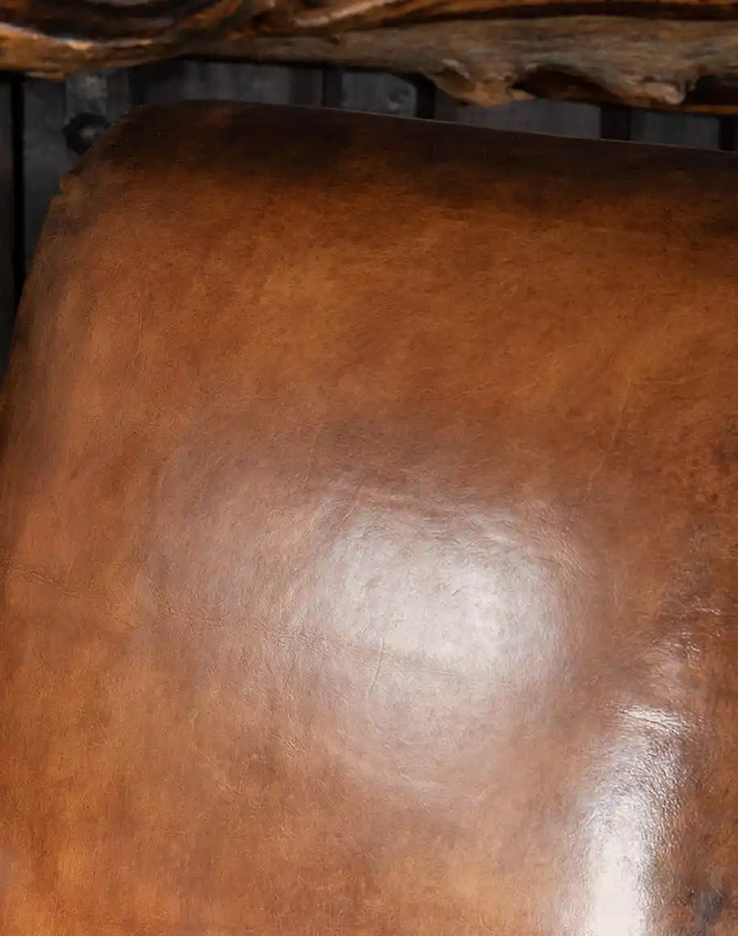 A close-up of the hand-burnished leather accents, highlighting the chair’s unique character and artisanal quality.