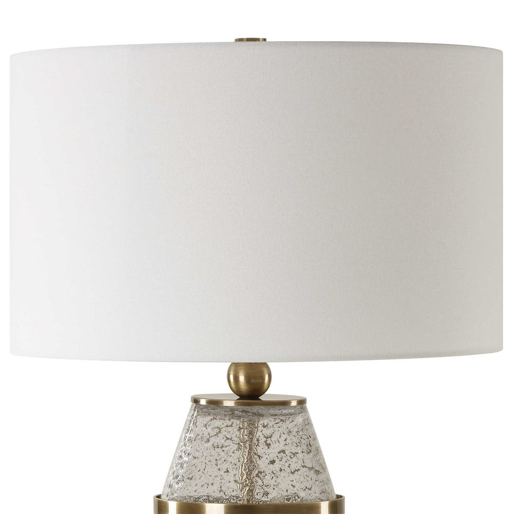 Modern hourglass lamp with gray-flecked glass, antique brass finish, and a round white linen shade.