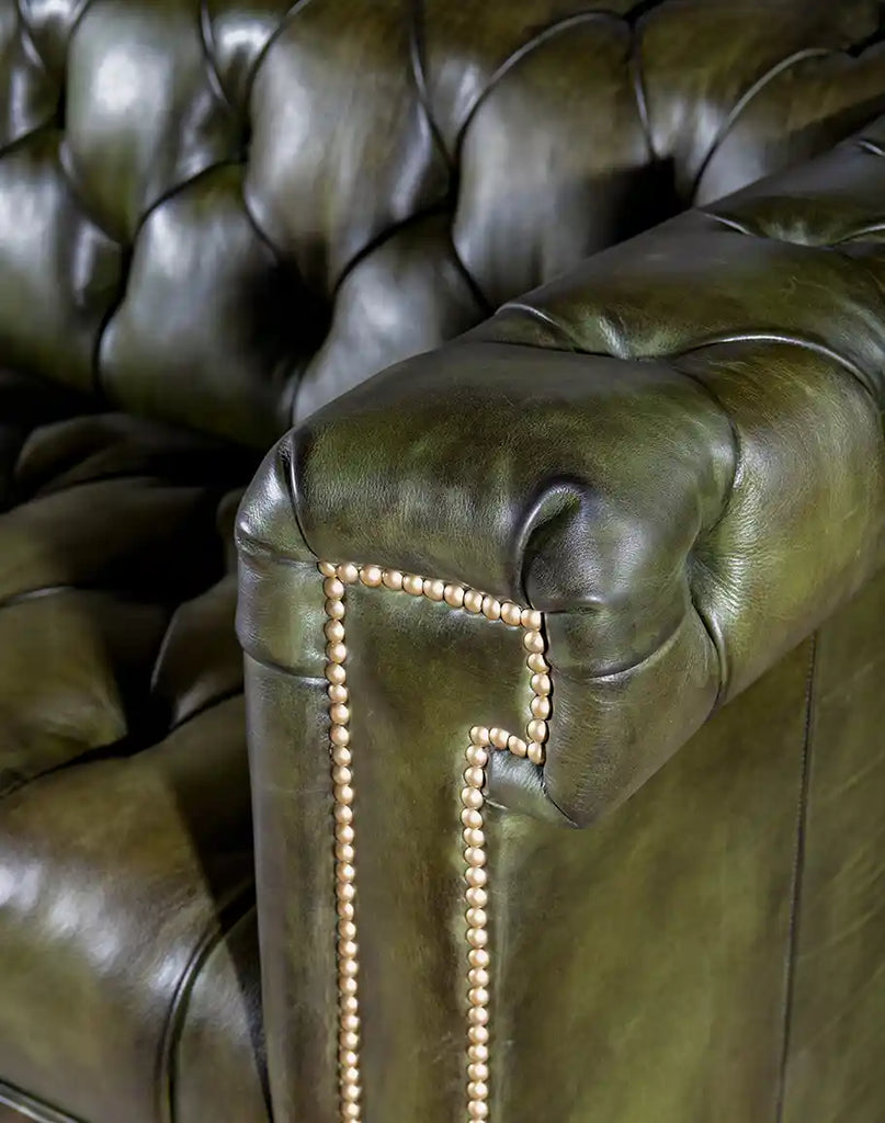 Close-up of the armrest, featuring fine leather craftsmanship and brass tacks.