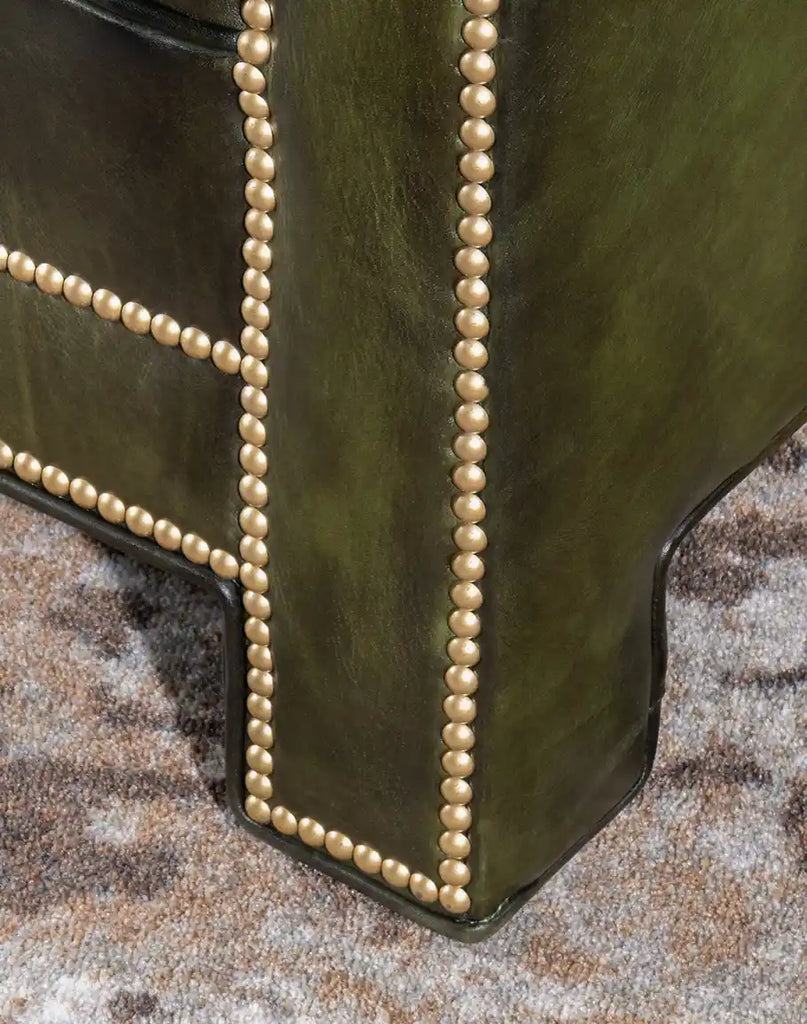 Detailed view of the sofa’s leg, emphasizing the brass nail trims and premium leather finish.