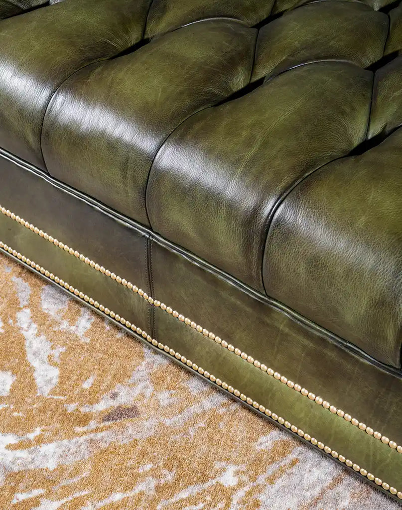 Showcasing the sofa’s solid construction, brass nail tack, and button tufting details.