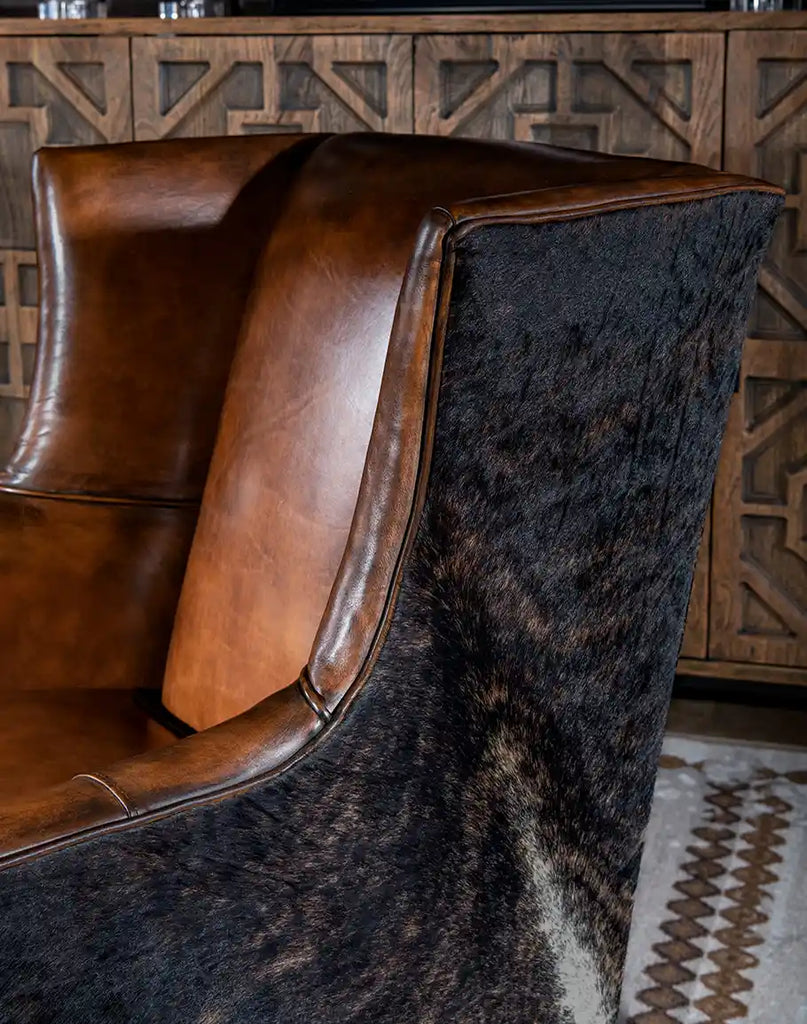 A side profile of the Westlife Leather Chair highlighting the sleek armrests and hand-burnished leather accents.