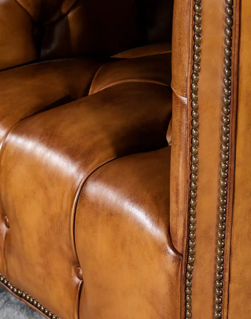 A detailed close-up of the Kingston Tufted Leather Chair’s hand-burnished leather, showcasing its luxurious texture and rich patina.