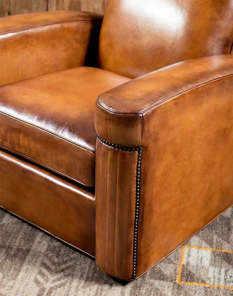 A side angle of the Yeager Swivel Chair with pleated leather upholstery and rustic brass accents.